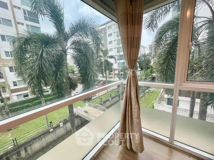 Spacious corner unit with large windows offering lush garden views in a modern apartment complex.