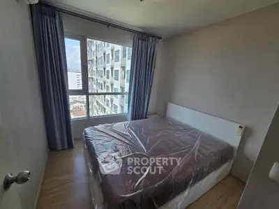 Cozy bedroom with large window and city view in modern apartment