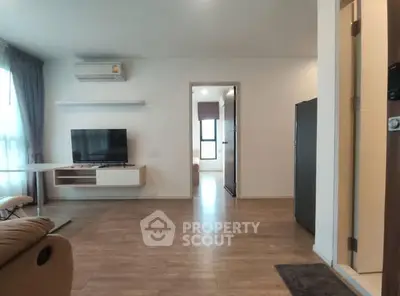 Modern living room with wooden flooring, TV, and air conditioning in a bright apartment.