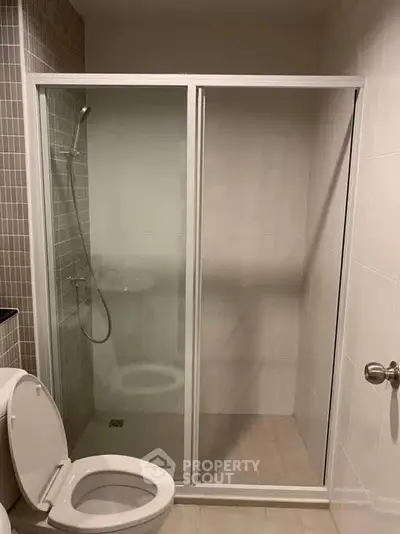 Modern bathroom with glass shower enclosure and tiled walls, perfect for contemporary living.