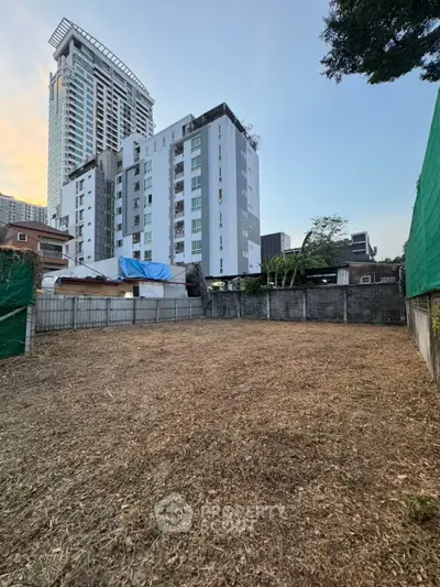 Prime vacant land with urban high-rise backdrop, ideal for development in a bustling city area.