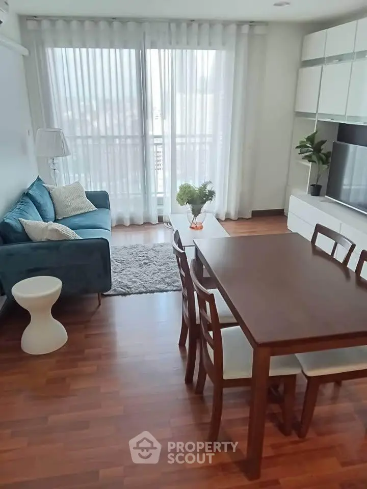 Modern living room with stylish furniture and natural light, featuring a cozy sofa and dining area.