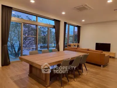 Spacious modern living room with large windows and elegant wooden dining table.