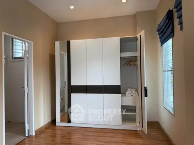 Spacious bedroom with modern wardrobe and wooden flooring