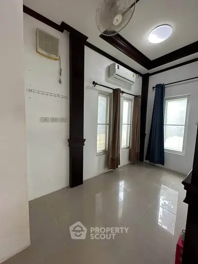 Bright room with air conditioning and large windows, ideal for versatile use.