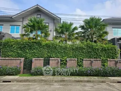Beautiful residential building with lush greenery and palm trees in front garden.