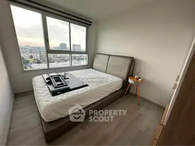 Modern bedroom with large window offering city views, featuring a stylish bed and minimalist decor.