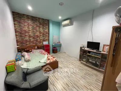 Cozy bedroom with modern decor, featuring a comfortable bed, stylish brick accent wall, and sleek air conditioning unit.