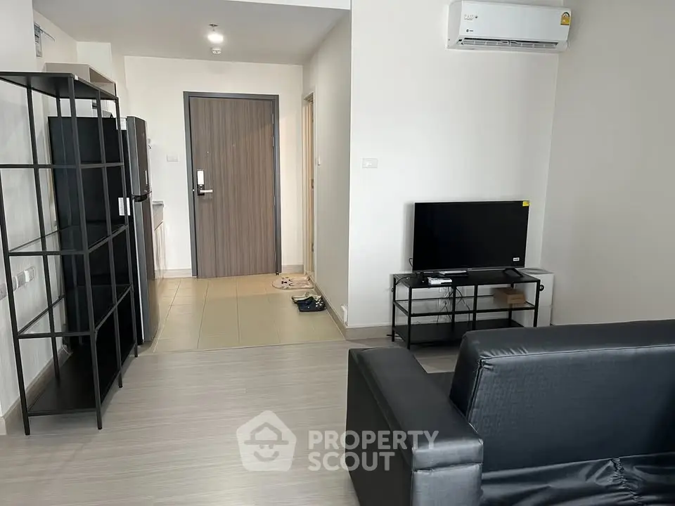 Modern living room with sleek black furniture and wall-mounted air conditioning
