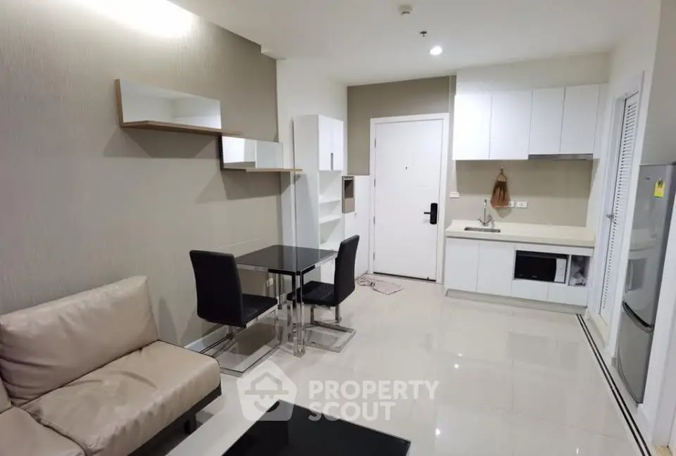 Modern open-plan living room and kitchen with sleek furniture and neutral tones.