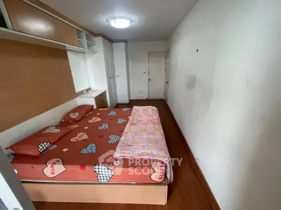 Cozy bedroom with wooden flooring and built-in shelves, perfect for a comfortable living space.