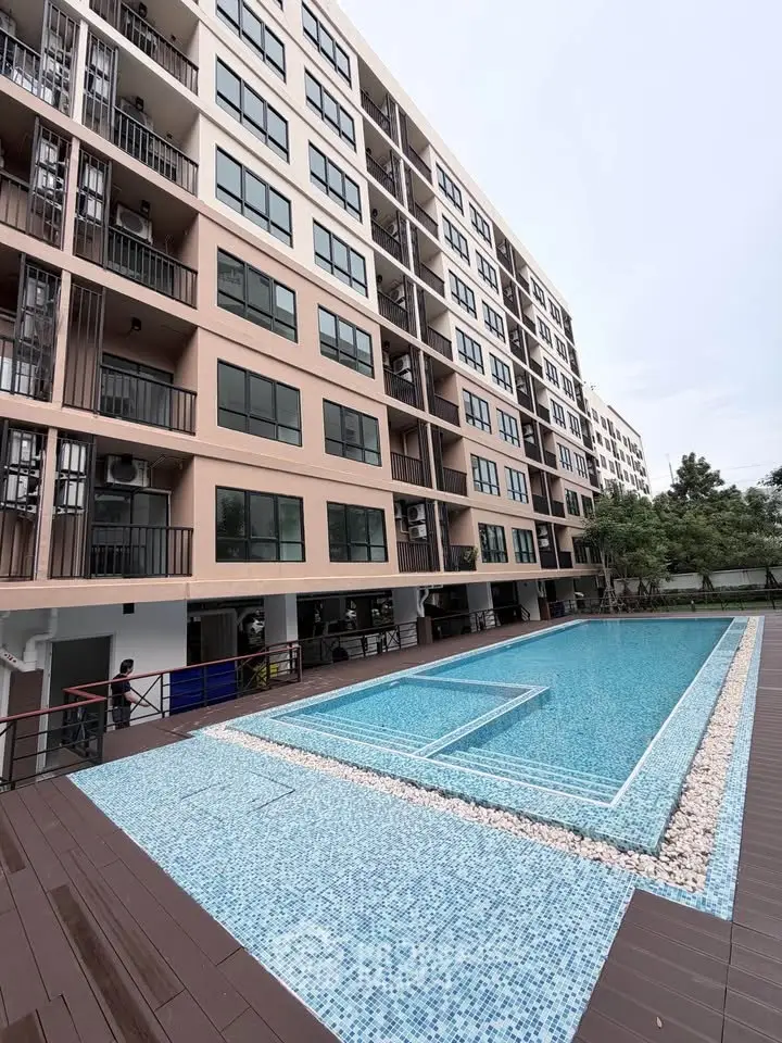 Modern apartment building with a stylish outdoor pool and spacious deck area.