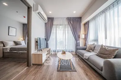Modern living room with open layout and natural light, featuring cozy sofa and stylish decor.