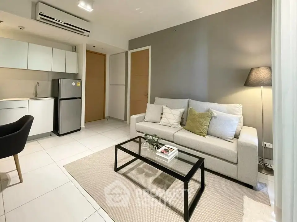 Modern living room with sleek furniture and open kitchen layout in a stylish apartment.