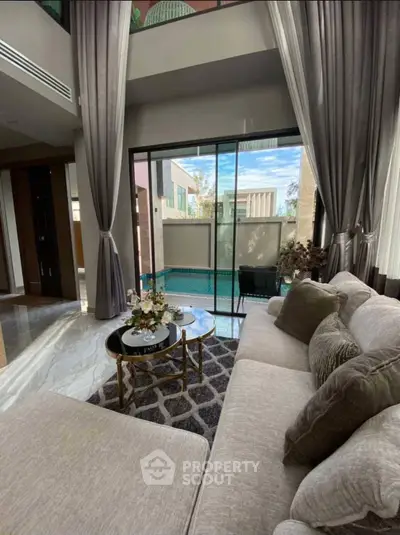 Luxurious living room with pool view, elegant decor, and floor-to-ceiling windows.