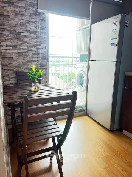 Charming kitchen with wooden dining set, fridge, and washing machine near balcony with view.