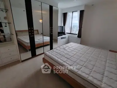 Spacious bedroom with large mirrored wardrobe and city view window in modern apartment.