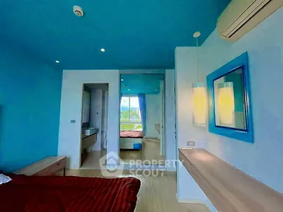Modern bedroom with blue accents and large mirror reflecting natural light.