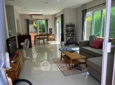 Spacious living room with modern decor and large windows overlooking greenery.