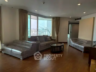 Spacious living room with large windows and modern furniture in a high-rise apartment.
