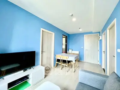Modern living room with blue walls, TV, and dining area in open layout.