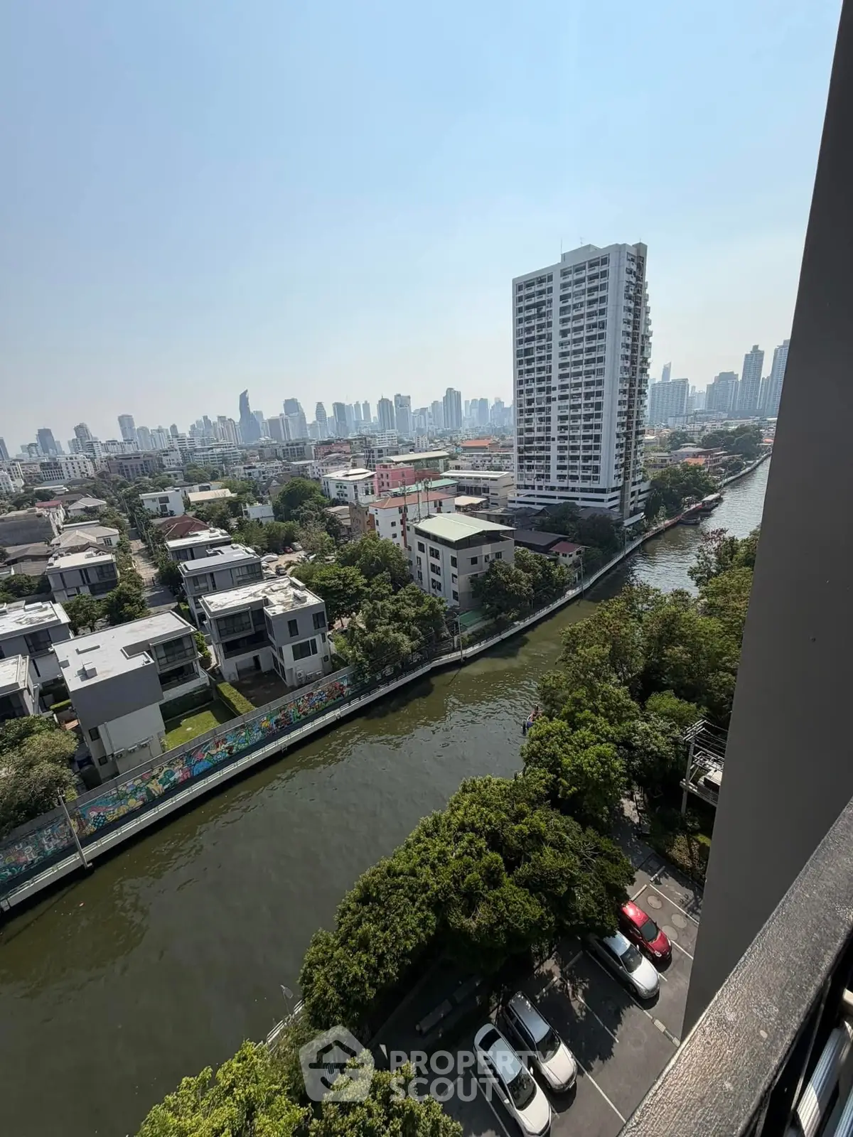Stunning cityscape view from high-rise balcony overlooking river and urban skyline.