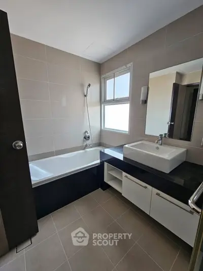Modern bathroom with sleek fixtures and a bathtub under a bright window.