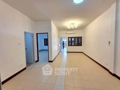 Spacious unfurnished living room with tiled flooring and bright lighting, ideal for customization.