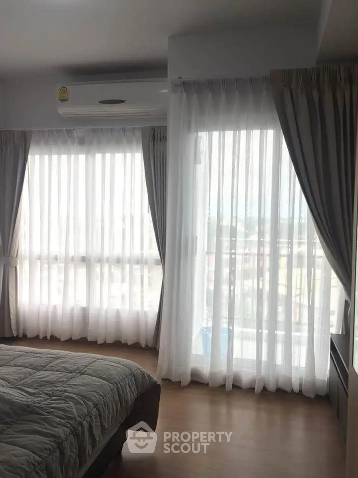 Bright bedroom with large windows and sheer curtains, offering ample natural light.