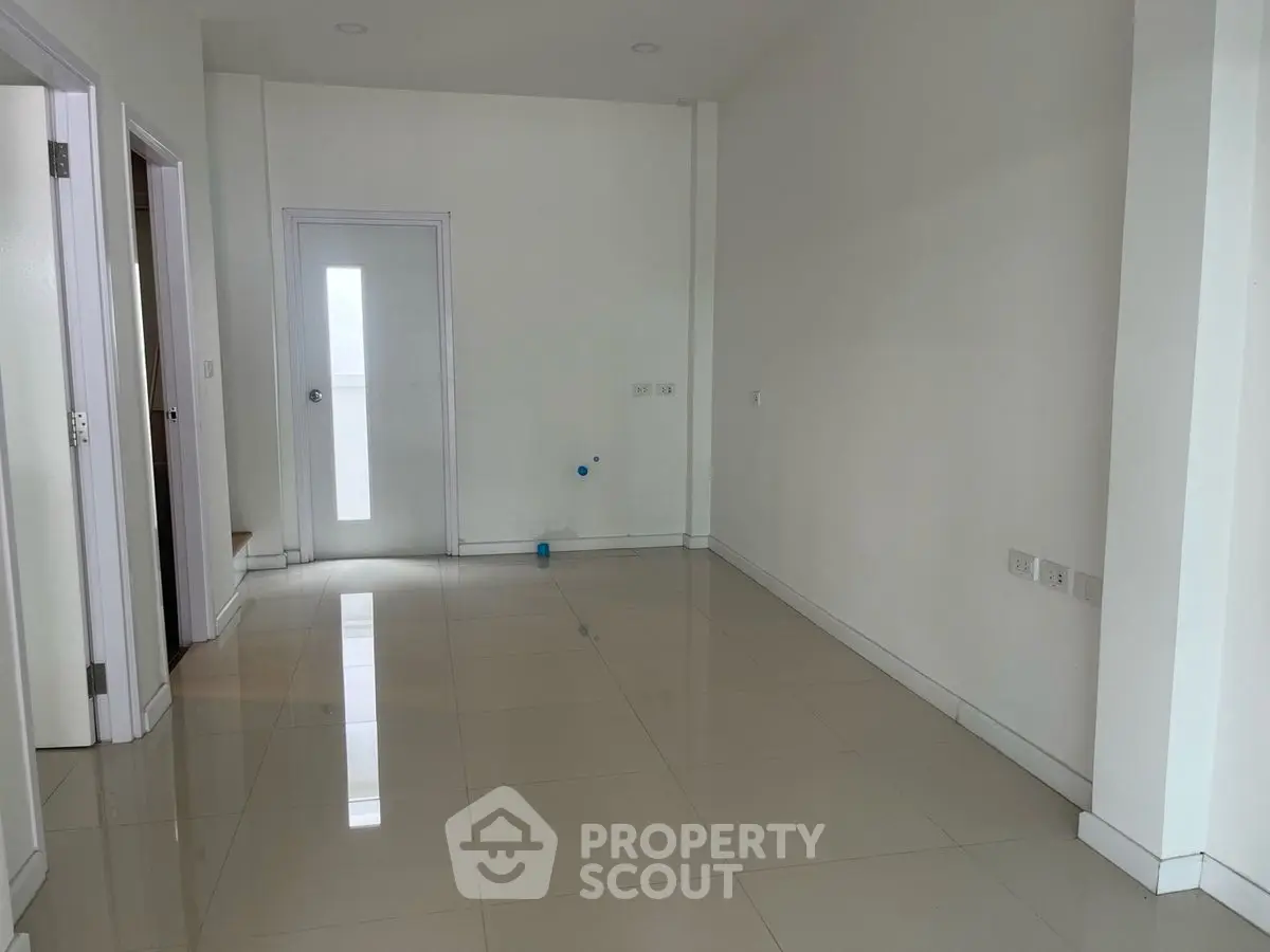 Spacious unfurnished room with glossy tiled flooring and white walls, ready for customization.