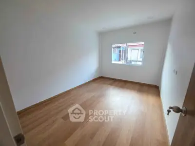 Spacious empty bedroom with wooden flooring and large window
