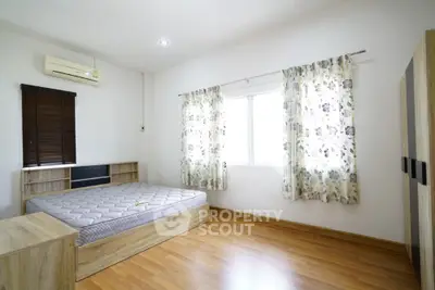 Spacious bedroom with wooden flooring and natural light