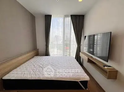 Modern bedroom with large window and wall-mounted TV, featuring sleek design and natural light.