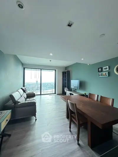 Spacious living room with modern furniture and large balcony offering stunning city views.