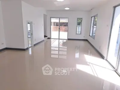 Spacious and bright living room with large windows and glossy tiled floors.