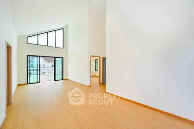 Spacious modern living room with high ceilings and large windows offering natural light and outdoor view.