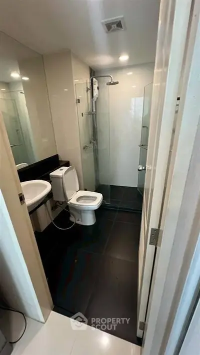 Modern bathroom with sleek black tiles and glass shower enclosure