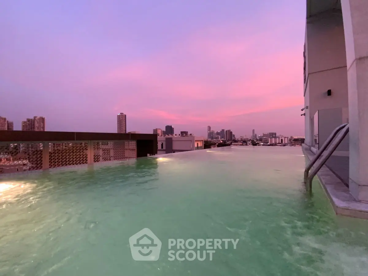 Stunning rooftop pool with panoramic city skyline views at sunset, perfect for luxury urban living.