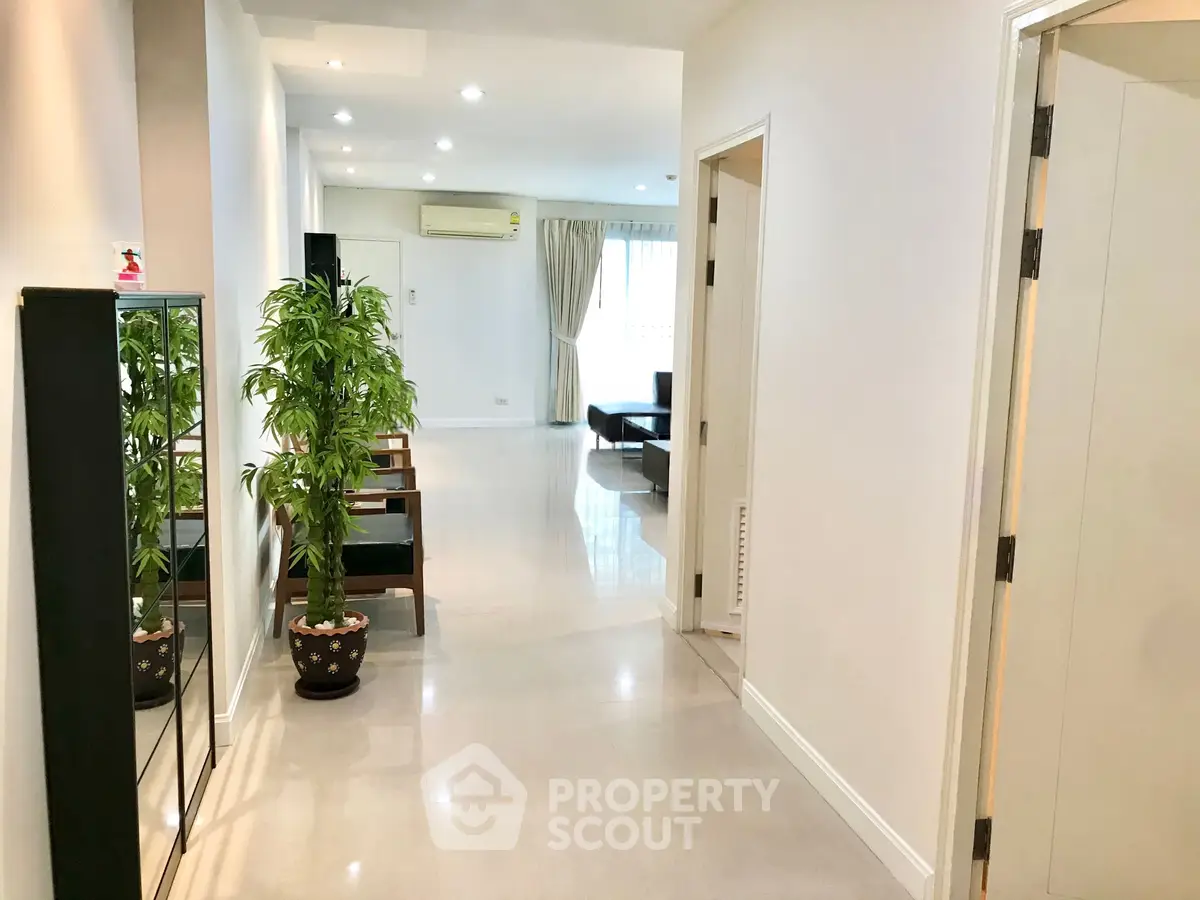 Spacious modern apartment hallway leading to a bright living room with stylish decor.