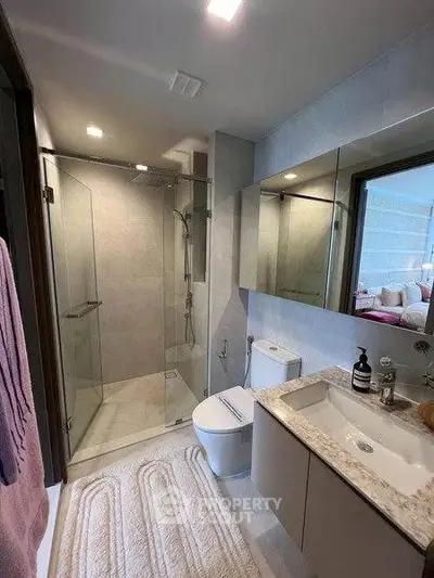 Modern bathroom with glass shower, sleek vanity, and elegant fixtures in a contemporary home.