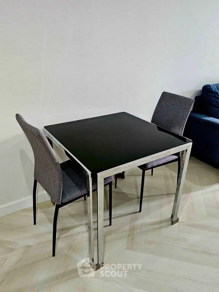Modern dining area with sleek black glass table and stylish chairs in a contemporary apartment.