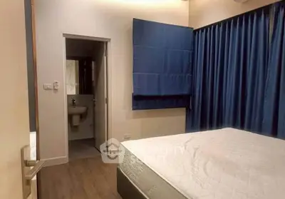 Cozy bedroom with blue curtains and ensuite bathroom, perfect for modern living.