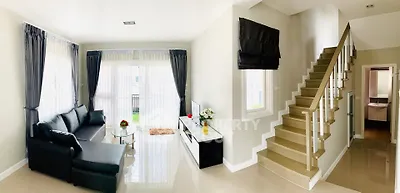 Spacious modern living room with elegant staircase and natural light.