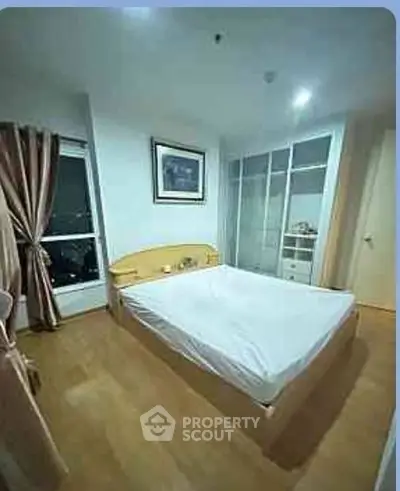 Cozy bedroom with large window and modern wardrobe in a stylish apartment.