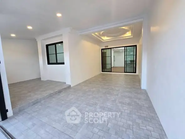 Spacious modern interior with elegant lighting and tiled flooring, perfect for versatile living space.