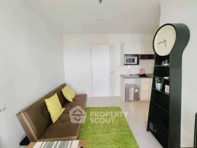 Modern living room with stylish clock and compact kitchen area.