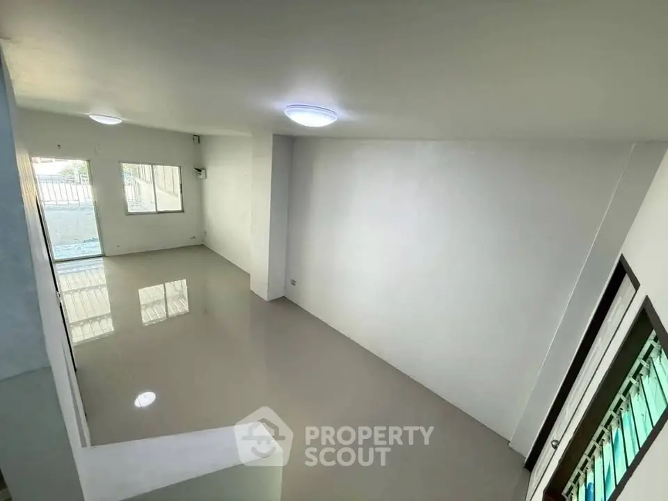 Spacious empty living room with large windows and glossy tiled floor.