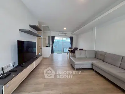 Spacious modern living room with sleek furniture and large TV, perfect for relaxation.