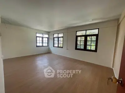 Spacious empty room with large windows and wooden flooring, perfect for customization.
