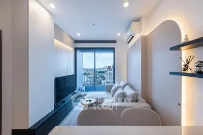 Modern living room with large windows and city view, featuring sleek furniture and ambient lighting.